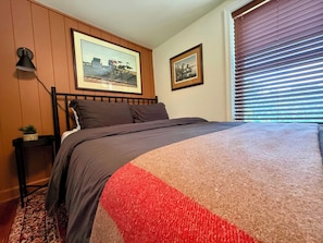 A bedroom with a bed, a nightstand, a lamp, and two framed pictures on the wall.
