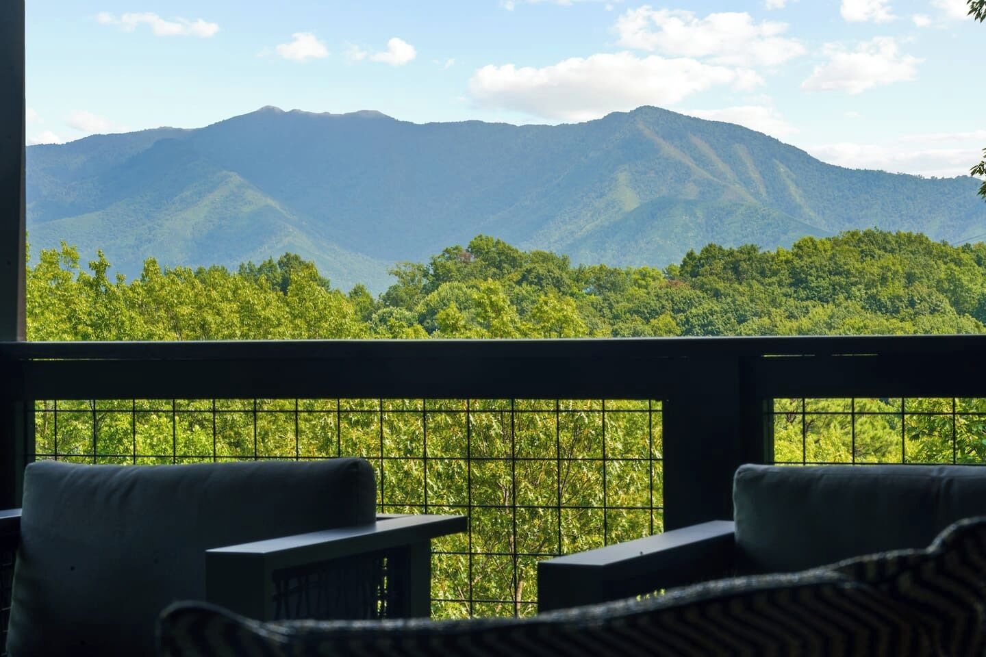Un balcón con vistas a una cordillera y un bosque denso.
