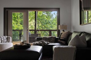 Ein Zimmer mit einer großen Schiebetür zum Balkon, einem Sofa, einem Beistelltisch und einer Lampe.