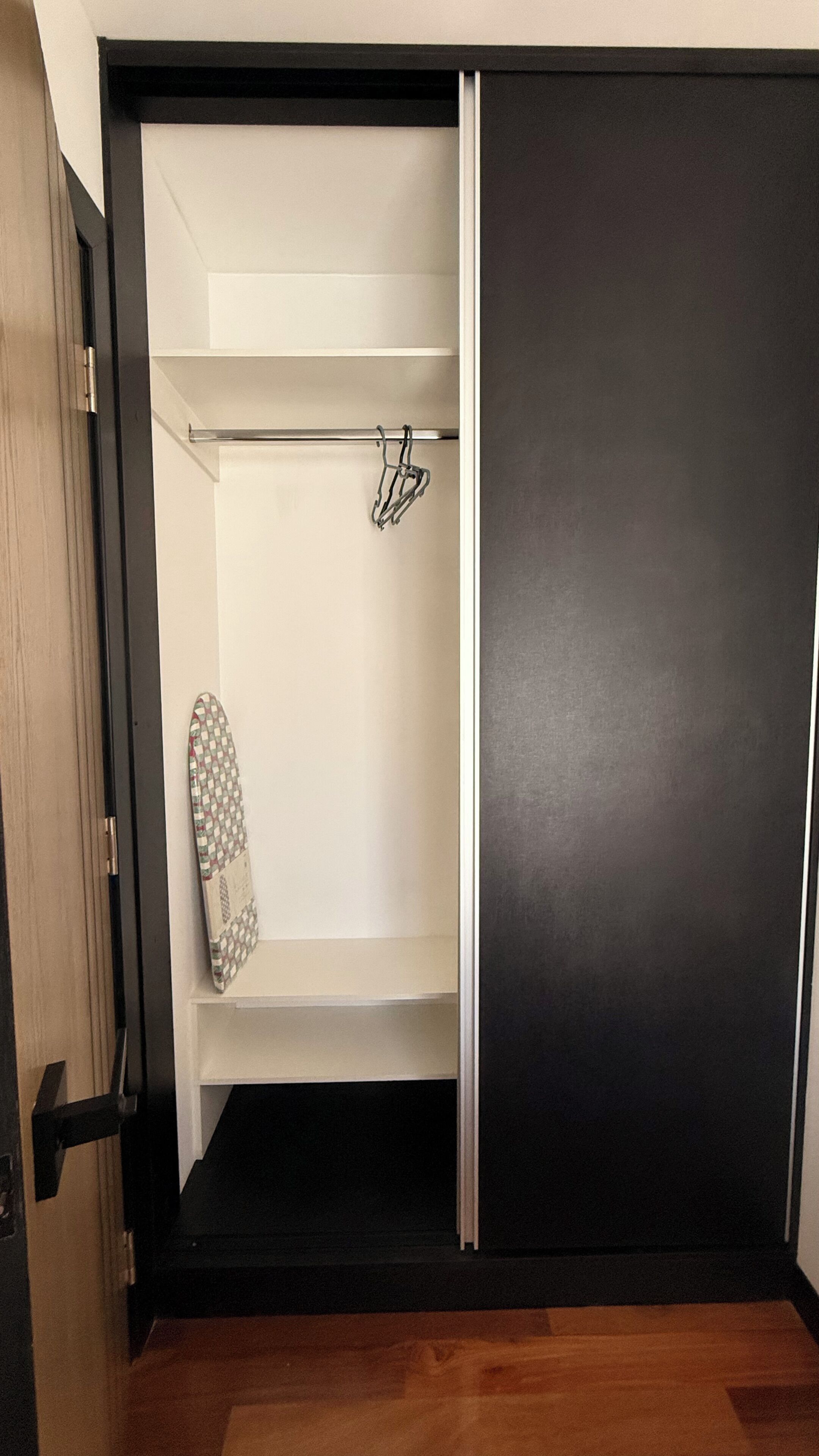 A walk-in closet with a sliding door, a hanging rack, and a shelf.