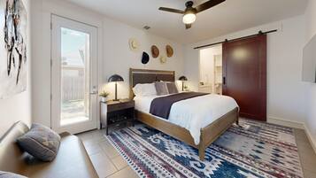 Une chambre à coucher avec un lit, des tables de chevet, un ventilateur de plafond et un tapis à motifs.