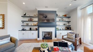 A modern living room with a fireplace, built-in shelves, and a flat-screen TV.