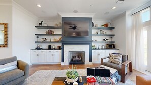 A modern living room with a fireplace, built-in shelves, and a flat-screen TV.