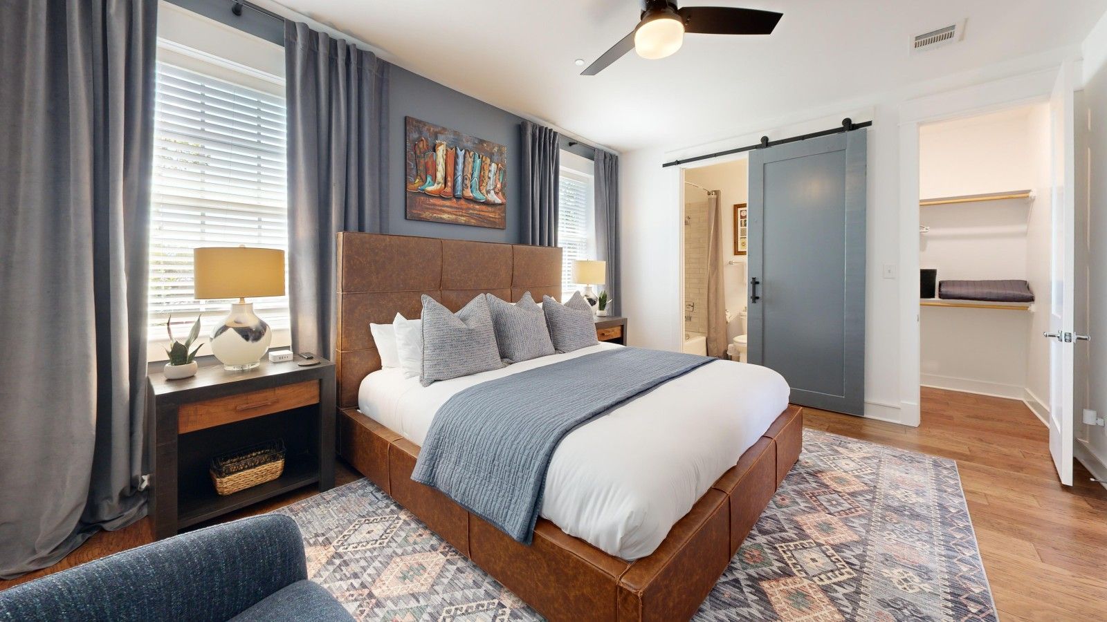 A bedroom with a bed, bedside tables, a lamp, a painting, and a sliding door.
