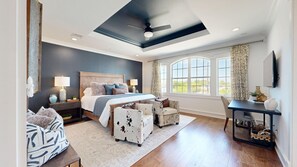 A bedroom with a large bed, a desk, and a chair.