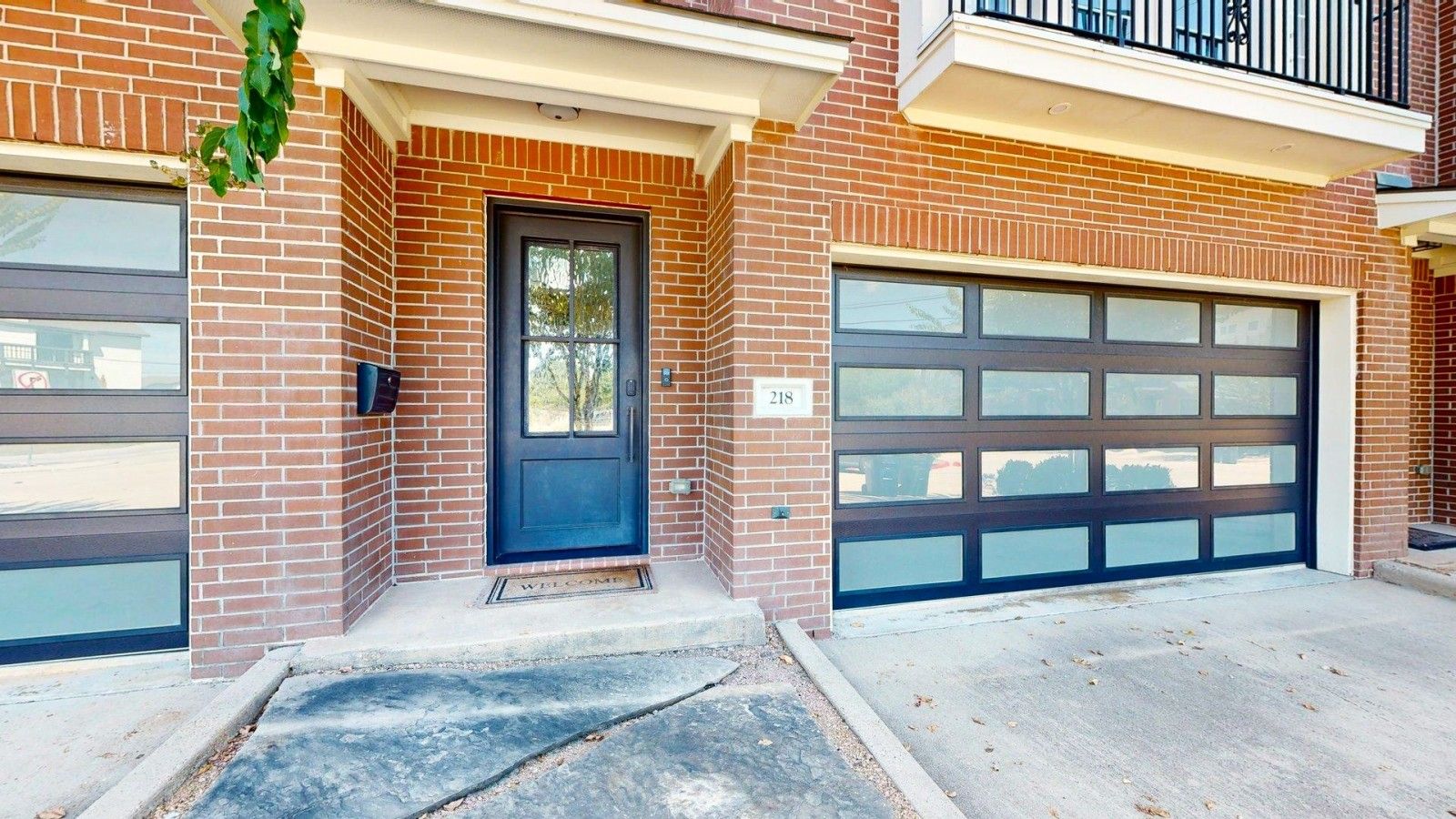 Un immeuble résidentiel avec une porte d’entrée sombre, une porte de garage et une boîte aux lettres.