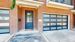 A residential building with a dark front door, a garage door, and a mailbox.