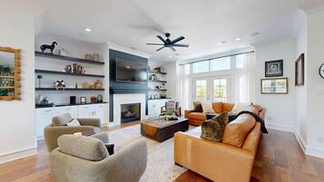 A modern living room with a fireplace, a large TV, and a seating area with a sofa and chairs.