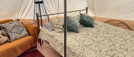 A tent with a bed, a chair, and a mannequin.