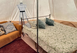 Una tenda con un letto, una sedia e un manichino.