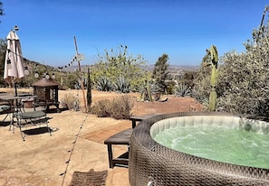 An outdoor hot tub area with a view of a desert landscape, surrounded by cacti and other desert vegetation.