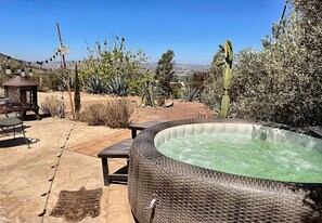 A hot tub in a garden with a pergola and outdoor furniture.
