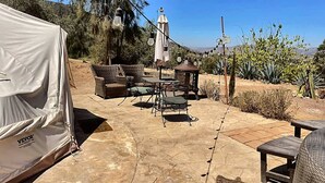 Eine Terrasse im Freien mit einem Zelt, Korbmöbeln und Lichterketten.