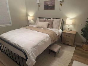 A bedroom with a bed, bedside tables, a nightstand, a lamp, and a small bench. - Sunswept 508 by ALBVR (Orange Beach)