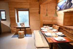 A wooden interior with a dining table set for four, a bench, and a window with a view. - Renovated sheep barn for rent in Serre Chevalier (05) - Sleeps 8 - 4 bedrooms - Sauna (Le Monêtier-les-Bains)