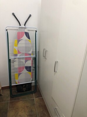 Un coin de pièce avec une armoire blanche et un étagère en métal sur laquelle est posée une serviette colorée.