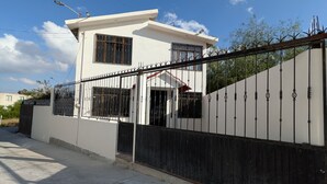 A modern two-story house with a gated entrance, a visible garage, and a clear sky.