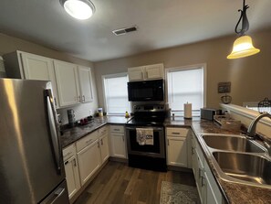 A kitchen with white cabinets, a stainless steel refrigerator, a microwave, and a stove. - CatalpaCorner 2-Bed Peace-filled/Sunroom/Turnkey/Mid-term/Monthly/Weekly (Springfield)
