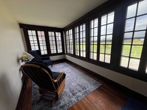 A room with a large bay window, a wooden rocking chair, and a blue armchair. - CatalpaCorner 2-Bed Peace-filled/Sunroom/Turnkey/Mid-term/Monthly/Weekly (Springfield)