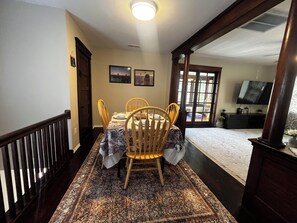 A dining area with a table set for four, wooden chairs, a patterned rug, and two framed pictures on the wall. - CatalpaCorner 2-Bed Peace-filled/Sunroom/Turnkey/Mid-term/Monthly/Weekly (Springfield)