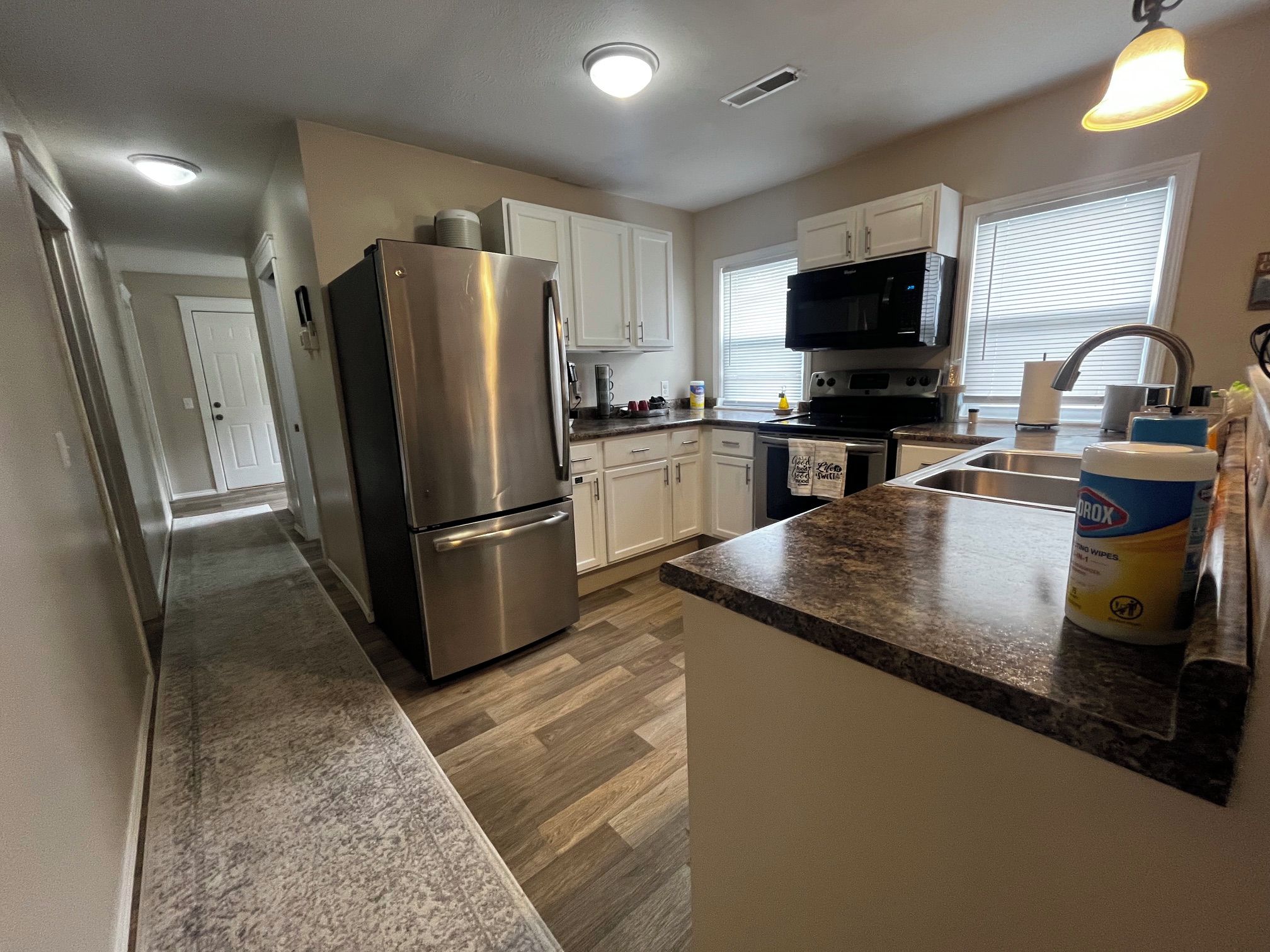 A modern kitchen with stainless steel appliances, a granite countertop, and a view to the living area.