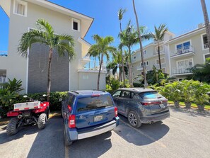A parking area with two vehicles, a red ATV, and a blue SUV.