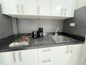 A kitchen with white cabinets, a black countertop, a coffee maker, a toaster, and a sink. - CORAZON de LOS CORALES (La Altagracia Province)