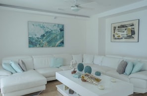 Un salon moderne avec un canapé blanc, une table basse blanche et deux tableaux abstraits accrochés aux murs.