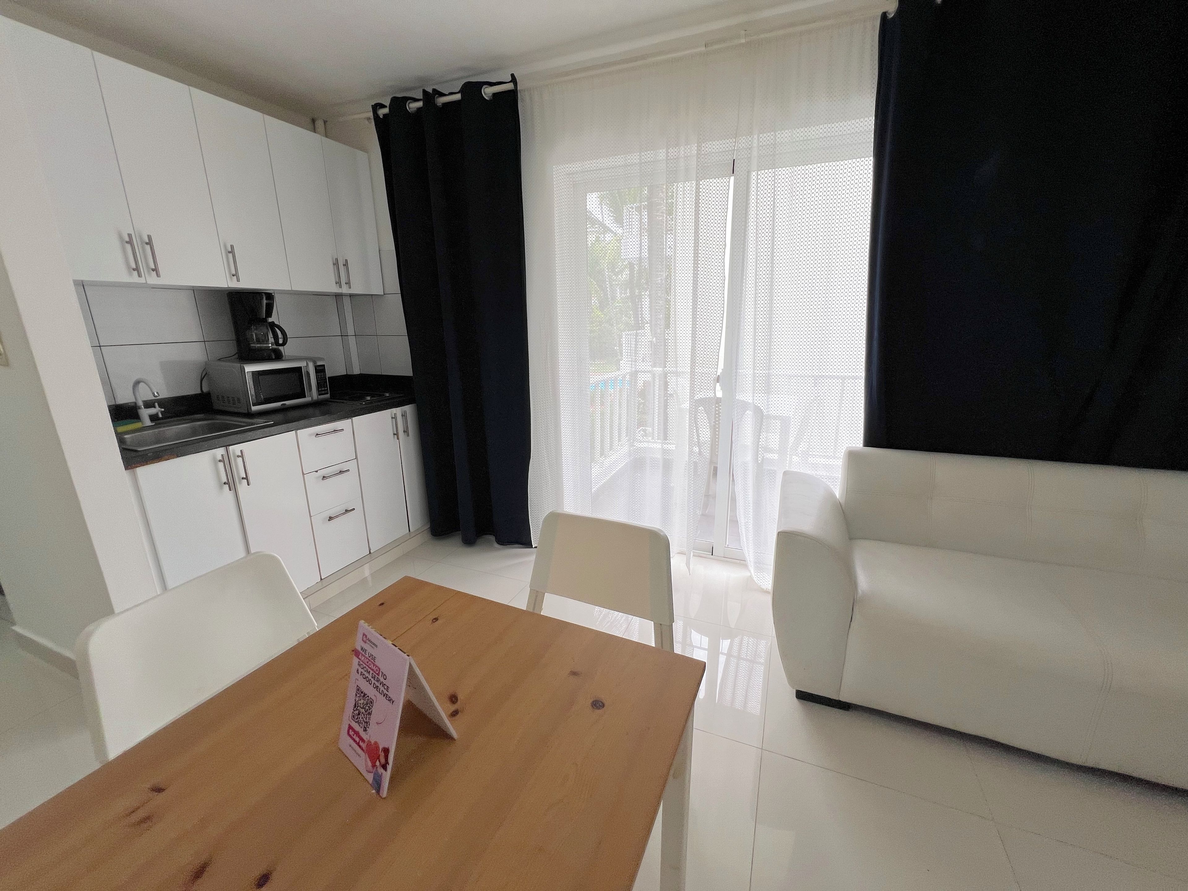 Un espacio habitable compacto con kitchenette, una mesa de comedor con un letrero y un sofá.