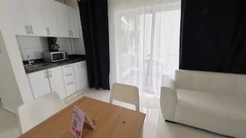 Un espacio habitable compacto con kitchenette, una mesa de comedor con un letrero y un sofá.