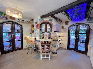 A cozy interior with a bar area, wine display, and a seating arrangement.