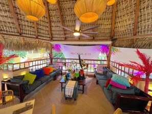 A spacious room with a thatched ceiling, multiple seating areas, and a central table with various items. - CORAZON de LOS CORALES (La Altagracia Province)