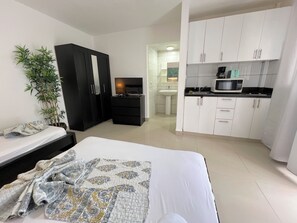 A bedroom with a bed, a TV, a wardrobe, a desk, a sink, and a microwave in the adjacent kitchenette. - CORAZON de LOS CORALES (La Altagracia Province)