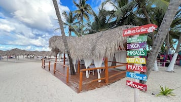 Een wellnesscentrum aan het strand met een houten terras en rieten parasols.