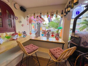 A bar area with two wicker chairs, a counter with various bottles, and a view of the street outside. - CORAZON de LOS CORALES (La Altagracia Province)