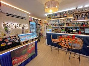 A sushi bar with a glass display case and a sign for 'SUSHI GOES HERE'.