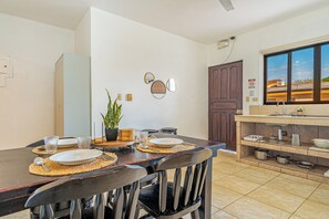 A dining area with a table set for two, chairs, a potted plant, and wall-mounted mirrors. - Playas del Coco Condo w/ Pool: Near Beach! (Playas del Coco)