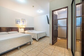 A hotel room with two beds, a flat-screen TV mounted on the wall, and a door leading to a bathroom. - Playas del Coco Condo w/ Pool: Near Beach! (Playas del Coco)