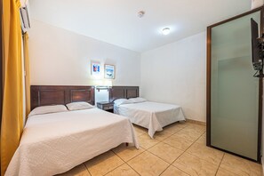 A hotel room with two beds, a nightstand, a lamp, a TV, and a sliding door. - Near Beach! Playas del Coco Condo w/ Pool (Playas del Coco)