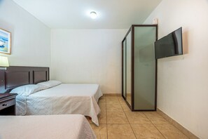 Ein Hotelzimmer mit zwei Betten, einem an der Wand montierten Fernseher und einem Gemälde.