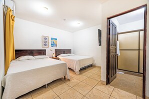 A hotel room with two beds, a nightstand, a lamp, and a door leading to a balcony. - 1 Mi to Beach: Playas del Coco Condo w/ Pool (Playas del Coco)