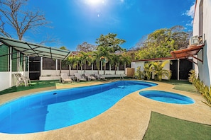 Ein Schwimmbecken mit Sonnenschirm, Liegestühlen und einem angelegten Garten.
