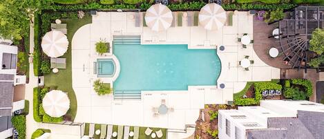 An aerial view of a hotel with a swimming pool, outdoor seating, and greenery.