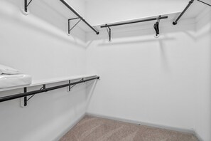 Una esquina de una habitación con una pared blanca, una alfombra color beige y una encimera blanca con una toalla.
