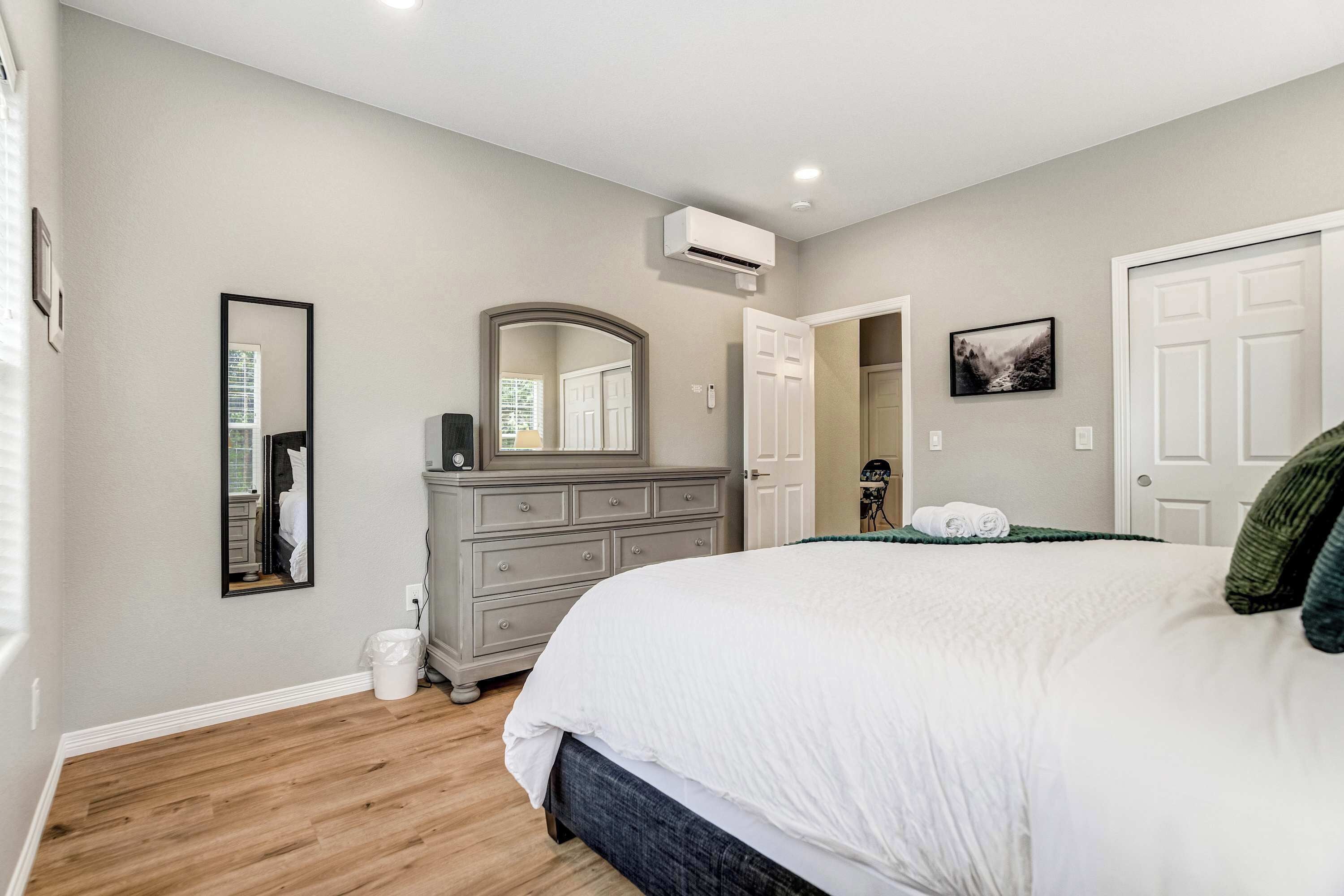A bedroom with a large bed, dresser, and a mirror.
