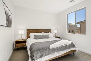 A bedroom with a bed, nightstands, a window, and a wall-mounted picture.