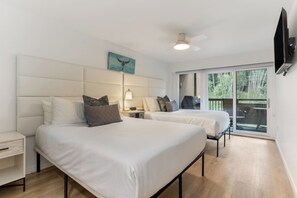 A hotel room with two beds, a ceiling fan, a mounted TV, and a balcony with a view of trees. - Fallridge Condo - Steps to Nordic Center and Bus (Vail)