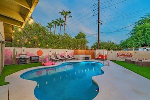 An outdoor swimming pool with lounge chairs, a barbecue area, and a decorative wall with a sunset mural. - 6 bdrm/ 5bdrm in Old Town Scottsdale with Casita, Game Room, and Pool! (Scottsdale)
