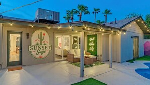Um edifício com o logotipo 'SUNSET Sage' e uma placa de néon 'Good Vibes Only'.