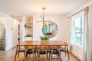 A dining area with a wooden table, chairs, a mirror, and a modern light fixture. - 6 bdrm/ 5bdrm in Old Town Scottsdale with Casita, Game Room, and Pool! (Scottsdale)